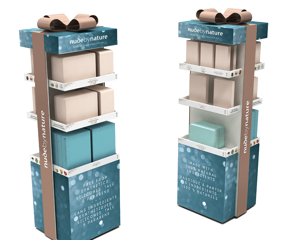 Two Nude by Nature corrugated floor stand retail displays designed to resemble gifts with three shelves and a bow on top